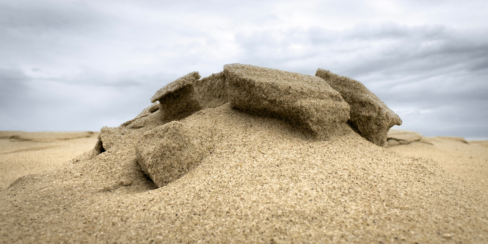 Sand dunes with weathered formations under a cloudy sky