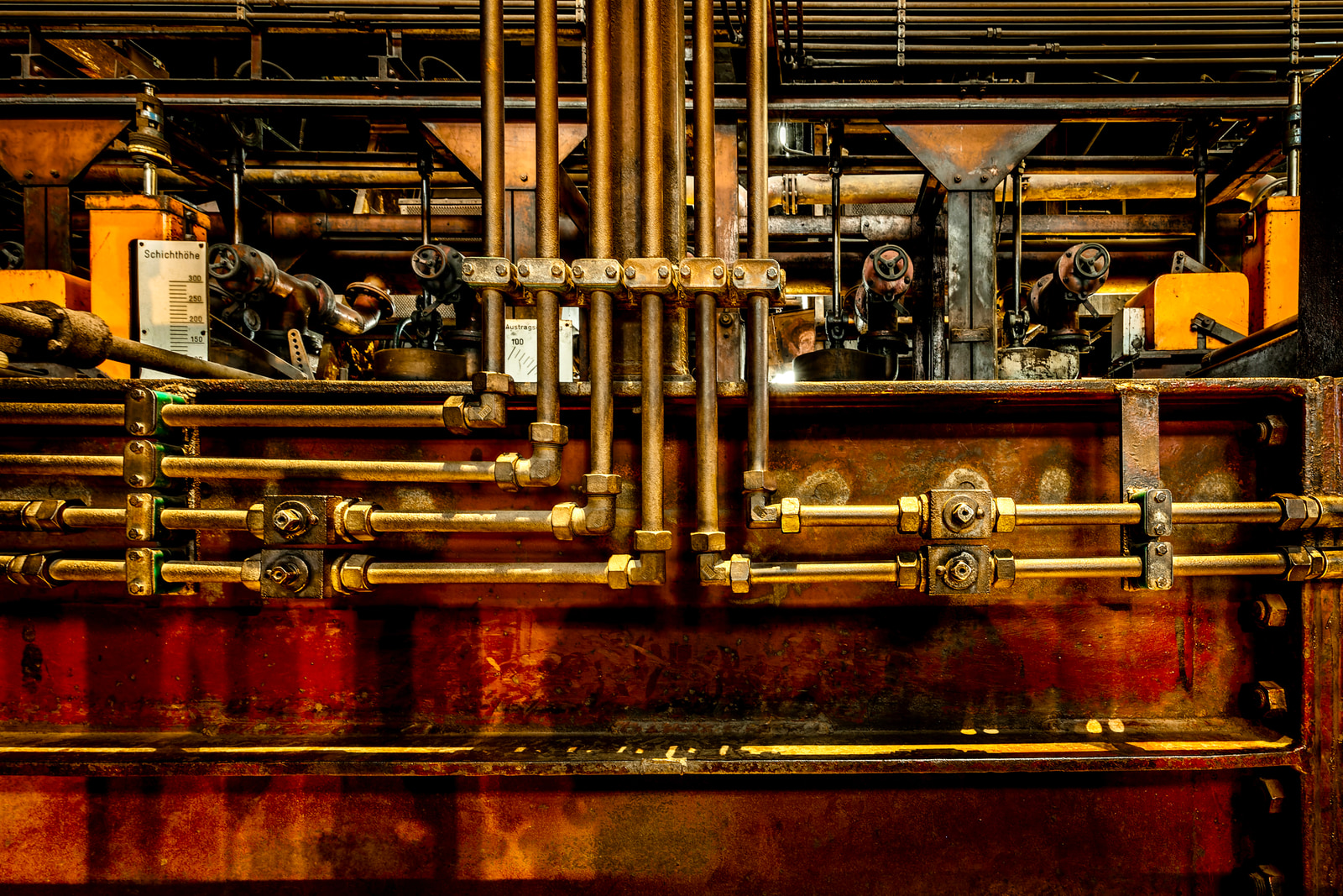 Close-up view of aged industrial machinery with brass fittings and pipes, showing intricate mechanical details and wear.